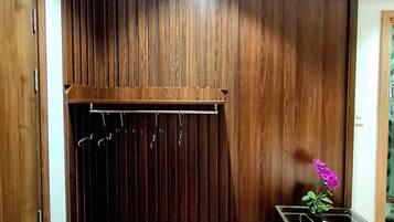 A room with a wooden slatted wall, a small bench, a shoe rack, and a trash bin.