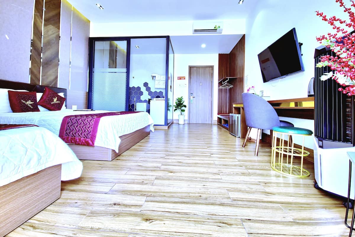Quarto de hotel moderno com cama, escrivaninha, cadeira e televisão.