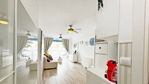 Un salon moderne avec un canapé, un coin repas avec une table et une cuisine équipée d’un réfrigérateur.