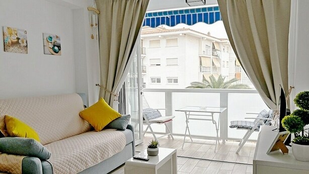 Un salon moderne avec un canapé, une petite table et un balcon équipé d’une table et de chaises.