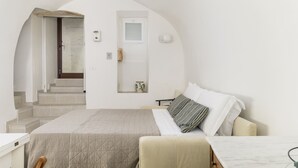 Una camera da letto dal design minimalista, con un letto, un tavolino e vista su una scala che conduce a una porta.