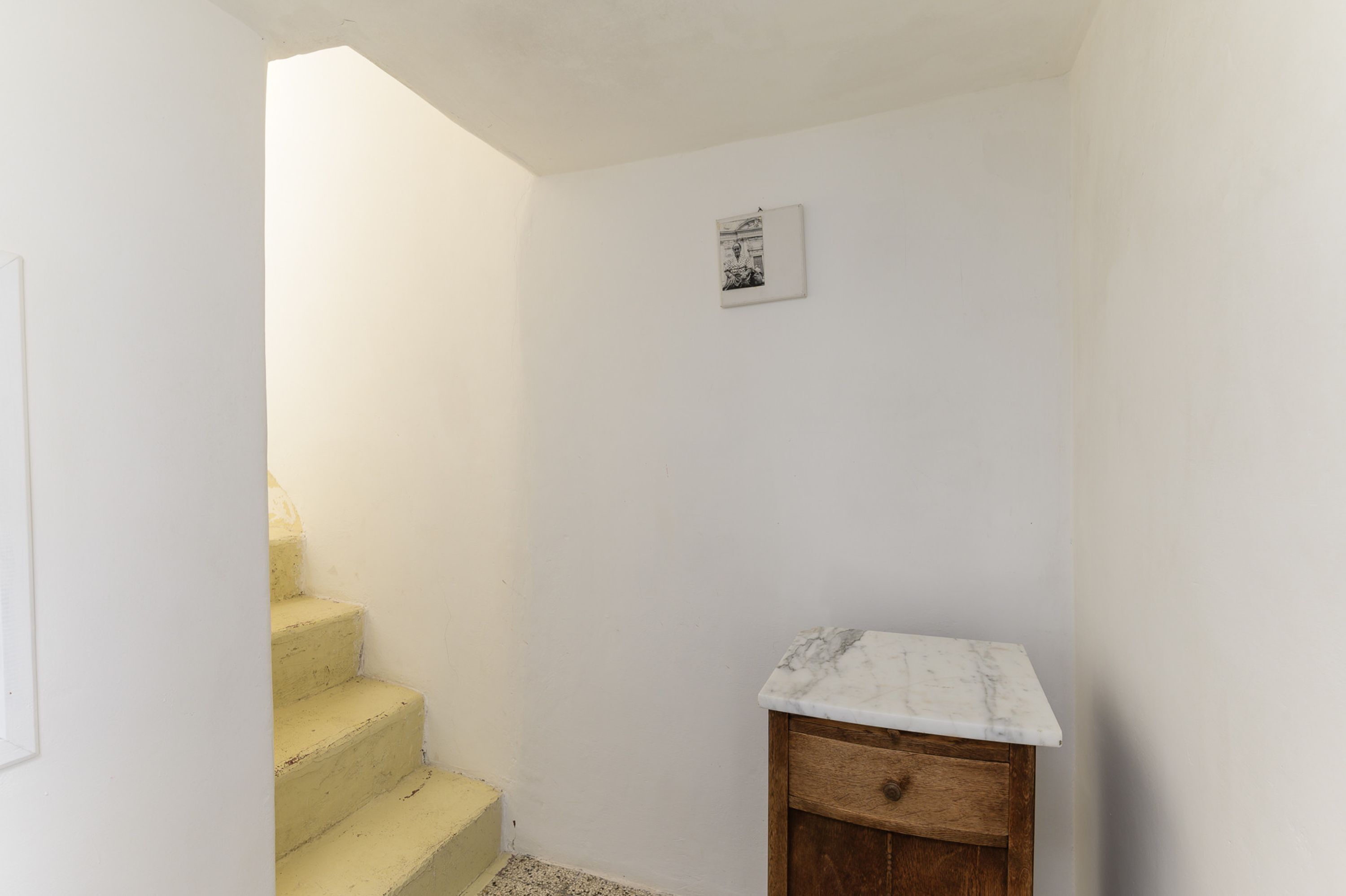 A narrow hallway with a wooden cabinet and a small picture on the wall.