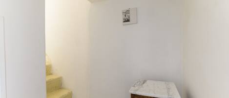 A narrow hallway with a wooden cabinet and a small picture on the wall.