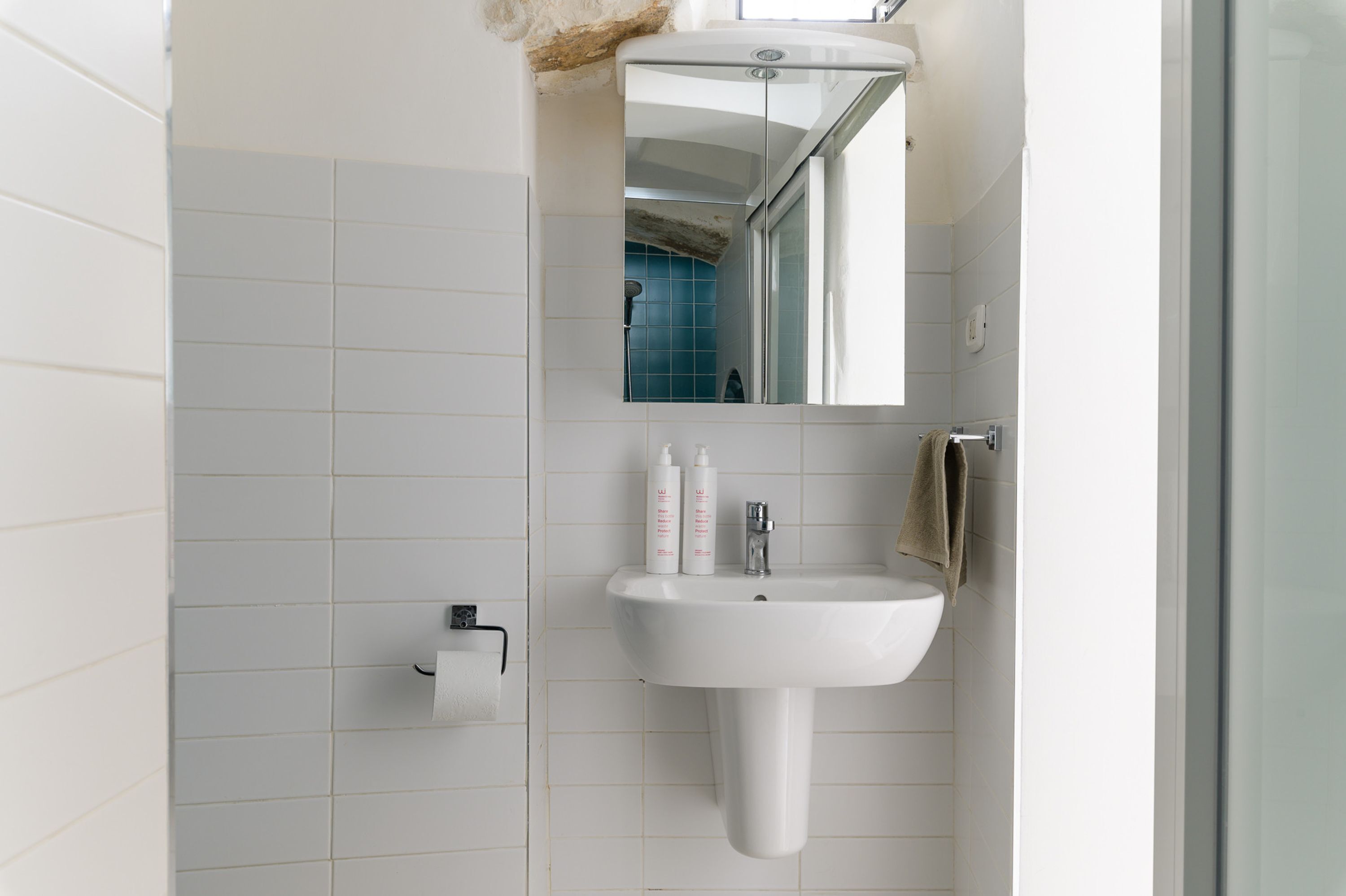 A bathroom with a white sink, a mirror, and a towel rack.
