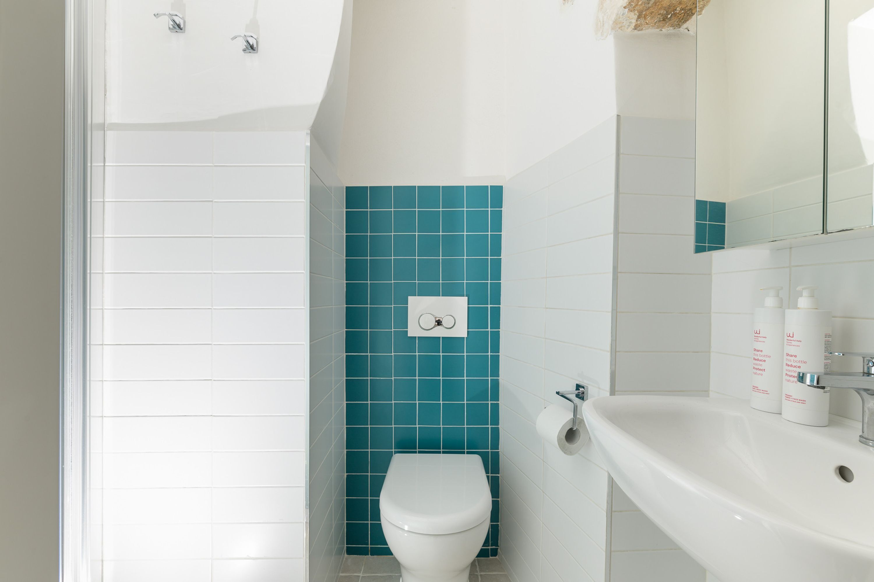 A bathroom with a white toilet, a sink, and a mirror.