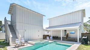 Ein modernes Haus mit Schwimmbad, einer überdachten Terrasse und einer Treppe zu einer Außenterrasse.