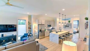A modern kitchen with white cabinets, a central island, and bar stools. - Rooftop Hot Tub 13 Beds Game Room (Nashville)