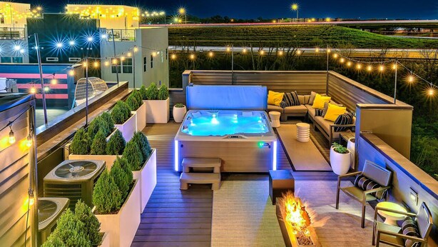 A rooftop patio with a hot tub, seating area, and outdoor lighting. - Rooftop Hot Tub 13 Beds Game Room (Nashville)