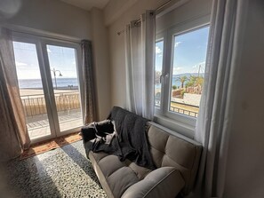Ein Wohnzimmer mit einer Couch, Meerblick und einem Balkon.