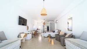 Un salon moderne avec un canapé, un coin repas et une cuisine en arrière-plan.