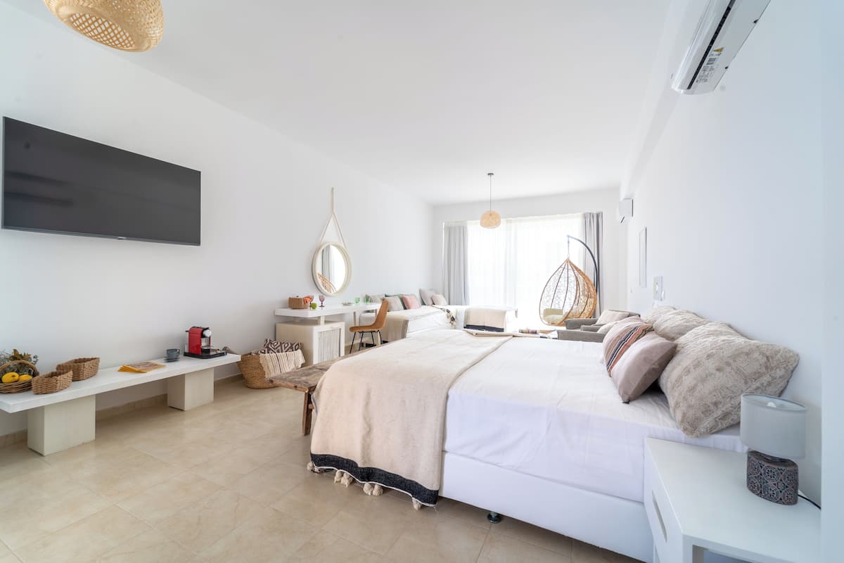 Un dormitorio moderno con una cama grande, un escritorio y un televisor montado en la pared.