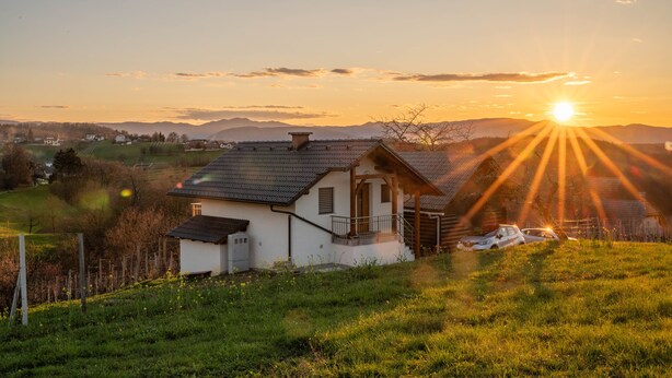 Ein Haus mit geneigtem Dach, einer kleinen Veranda und einem davor geparkten Auto.