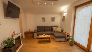 Ein Wohnzimmer mit Ecksofa, Couchtisch, Kamin und Wand-Fernseher.