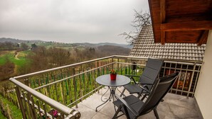 Ein Balkon mit Tisch und Stühlen mit Blick auf eine ländliche Landschaft.