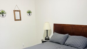 Ein Schlafzimmer mit einem großen Bett, einem Nachttisch mit Lampe und zwei Wandpflanzen.
