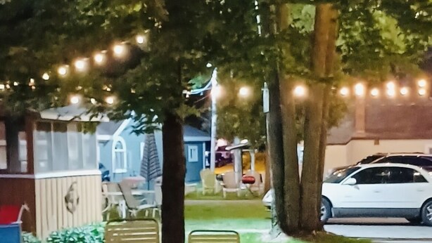 Ein Sitzbereich im Freien mit zwei Stühlen unter einem Baum, umgeben von Lichterketten.