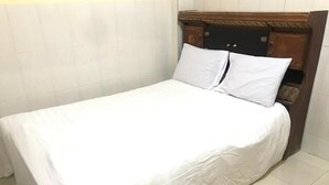 A neatly made bed with white linens in a room with a wooden headboard and tiled floor. - Hotel O Wisma Gading Syariah (Pemalang)
