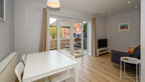 A modern living room with a white table and chairs, a grey sofa, and a TV. - Dings: Central Bristol House by STAE-Homes (Bristol City)