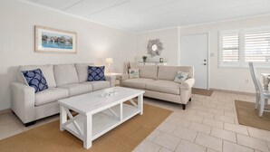 A living room with two sofas, a coffee table, a framed picture on the wall, a lamp, and a decorative mirror.