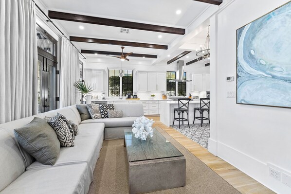 A modern living room with a sectional sofa, a coffee table, and a kitchen in the background.