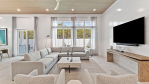 A modern living room with a sectional sofa, a coffee table, and a flat-screen TV mounted on the wall. - Seven Palms Pinnacle|Easy Beach Access|New Construction|Private Pool|Gulf Views (Inlet Beach)