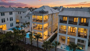 A multi-story hotel with balconies, a swimming pool, and a sunset sky. - Seven Palms Pinnacle|Easy Beach Access|New Construction|Private Pool|Gulf Views (Inlet Beach)
