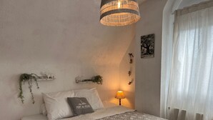 Een netjes ingerichte slaapkamer met een bed, een bedlampje en wandplanken met planten.