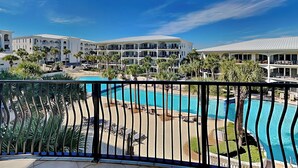 A hotel with a pool, palm trees, and a clear blue sky.