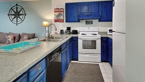 A kitchen with blue cabinets, a white stove, a dishwasher, and a ceiling fan. - Island Home #102 | Close to Beach and Destin Harbor (Destin)