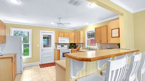 A kitchen with wooden cabinets, a white refrigerator, a microwave, and a ceiling fan. - Expansive Ranch on 2,001 Acres | Shared Pool & Hot Tub + Trails (Johnson City)