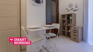Une pièce compacte et moderne, dotée d’un bureau blanc, de deux chaises, d’une bibliothèque et d’une horloge murale.