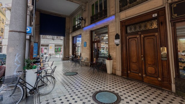 L’entrée d’un hôtel avec un sol à carreaux, un vélo garé à l’extérieur et une pancarte indiquant une vente.