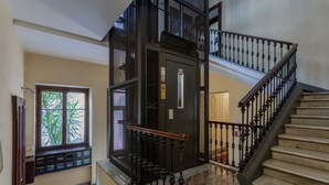 Un magnifique escalier avec une rampe noire et une main courante en bois, menant à un palier doté d’une porte équipée d’une serrure de sécurité.