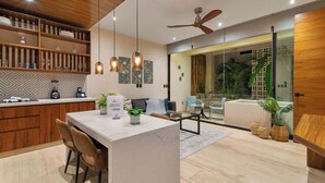 Une cuisine moderne avec des meubles en bois, un îlot en marbre, des luminaires suspendus et un ventilateur de plafond.