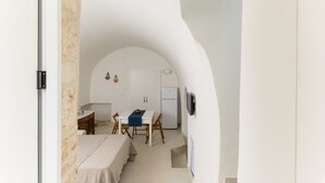 Een compacte keuken met witte kastjes, een koelkast, en een eethoek met een tafel en stoelen.
