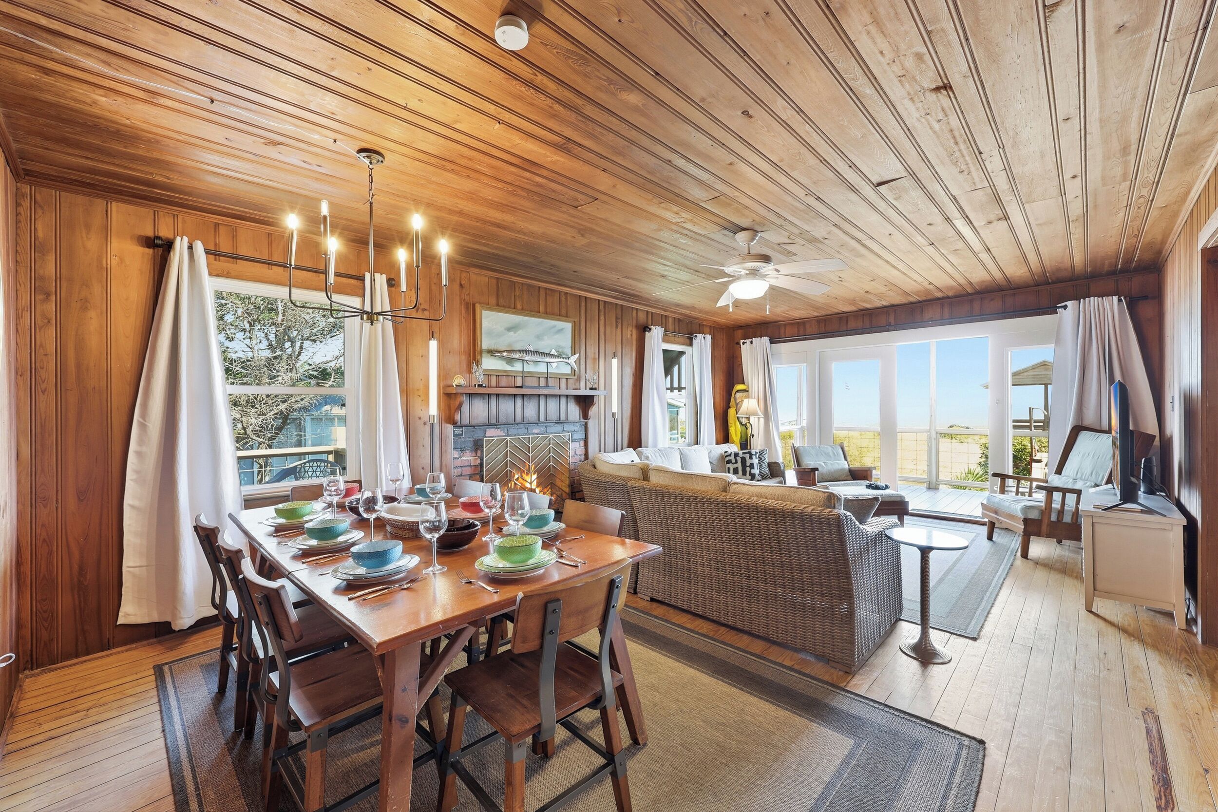 A wooden interior with a dining table set for four, a sofa, and a ceiling fan.