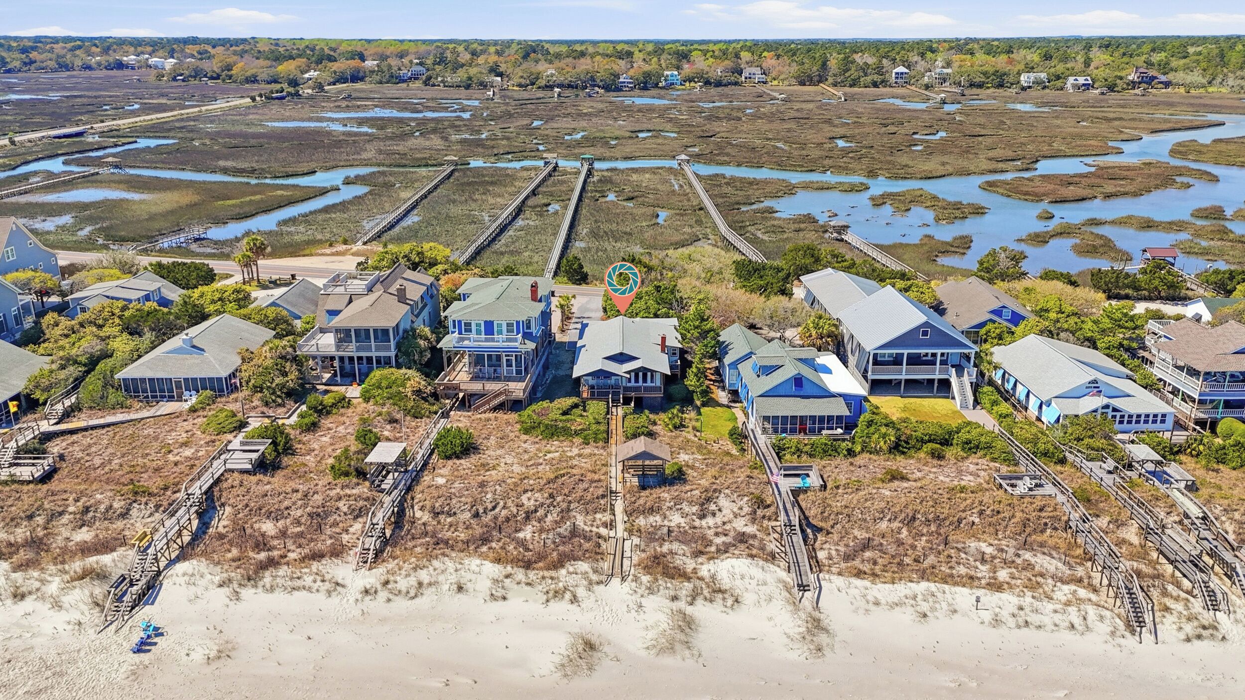 A coastal property with multiple houses, a pier, and a beach.