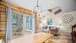 A cozy interior with a wooden dining table, a sofa, and a large wall clock. - Nature Adventure with Access to Exclusive Golf (Sunriver)
