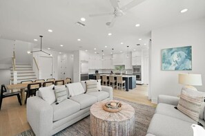 A modern living room with a grey sofa, a round coffee table, and a dining area with a wooden table and chairs.
