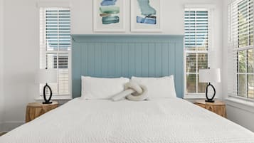 A neatly made bed with white linens, a blue headboard, and two bedside tables with lamps.