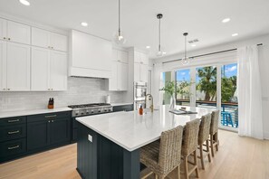 A modern kitchen with dark cabinetry, white countertops, and a central island.