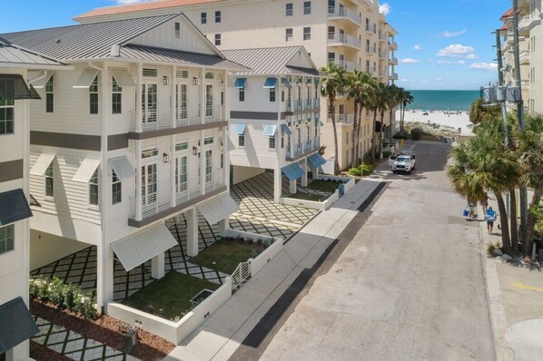 Ein mehrstöckiges Hotel mit Balkonen, einem gepflasterten Weg und Blick auf den Strand.