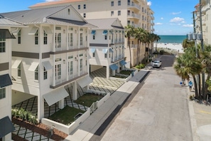 Un hôtel à plusieurs étages doté de balcons, d’une promenade dallée et offrant une vue sur la plage.