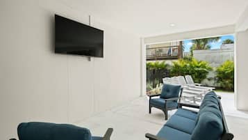 A modern living room with a flat-screen TV mounted on the wall, a sofa, and a coffee table.