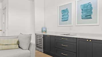 A modern kitchen with dark cabinets, a white countertop, and two framed artworks on the wall.