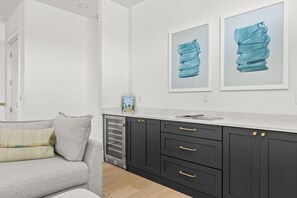 Eine moderne Küche mit dunklen Schränken, einer weißen Arbeitsplatte und zwei gerahmten Kunstwerken an der Wand.