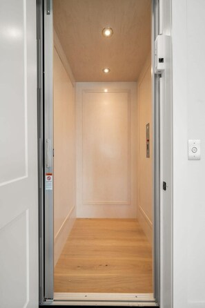 Ein schmaler Aufzug mit Holzboden und schlichter Wand.