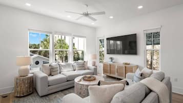 A modern living room with a grey sofa, a coffee table, and a TV mounted on the wall.