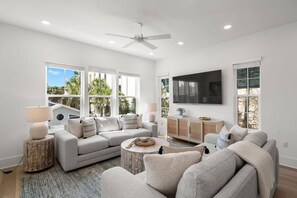 A modern living room with a grey sofa, a coffee table, and a TV mounted on the wall.