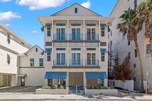 A multi-story building with a central entrance, balconies, and a gated driveway.